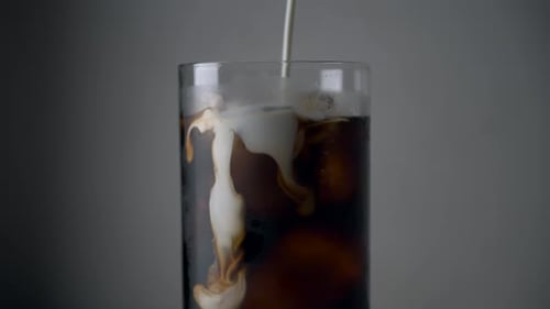 Creamy Milk Being Poured into Iced Coffee