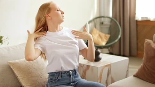 Young Woman Fanning Herself, Feeling Hot Indoors