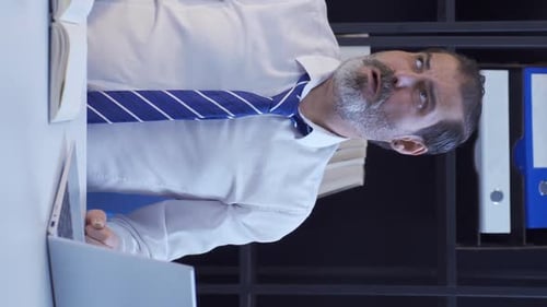 Tired Businessman Loosening Tie at Office Desk