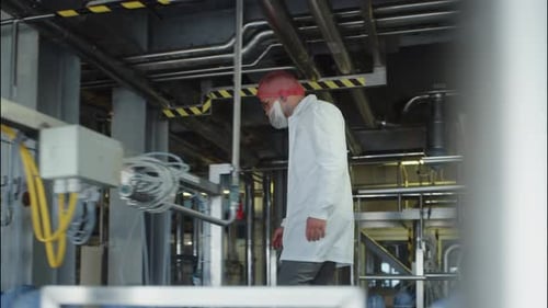 Ouvrier d'usine inspectant une chaîne de transformation industrielle