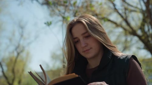 Woman Reading a Book Outdoors in the Park