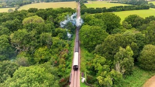 Aerial drone footage captures a vintage steam locomotive and carriages, evoking a bygone era as it j