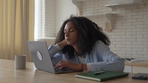 Woman Works on Laptop in Kitchen Setting