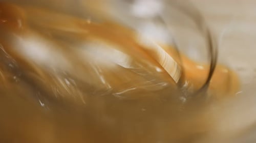 Mischen von frischen Eiern mit einem Stahl-Handmixer in einer Glasschale