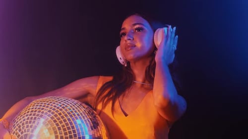 Woman Poses with Disco Ball Wearing Headphones at Night