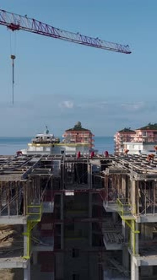 Vertical Video Construction Site Near Sea with Tower Crane and Workers