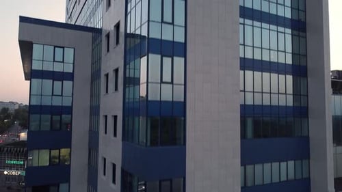 ein hohes Gebäude mit Balkon und Himmelsblick auf die darunter liegende Stadt in der Abenddämmerung oder Morgendämmerung mit ein paar Personen