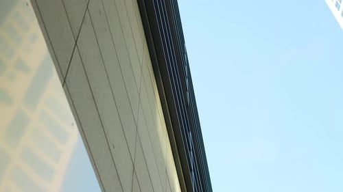 Looking up at a modern building's edge against a clear sky.
