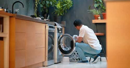 Man Loading Clothes into Washing Machine at Home