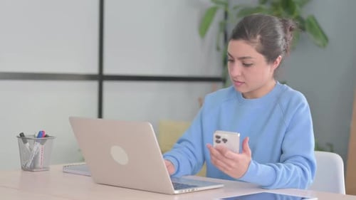Woman Uses Laptop and Phone at Desk