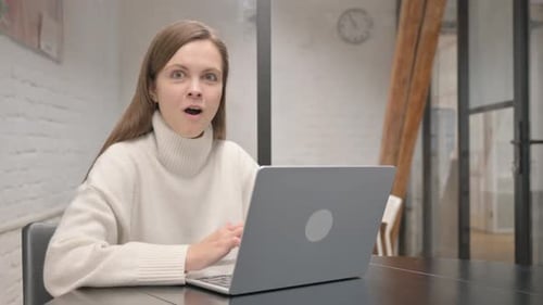 Woman Reacts to Content on Laptop in Office