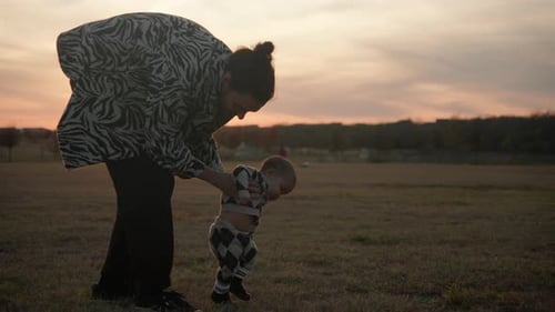 Young dad supporting his baby and teaching him how to walk. Slow motion