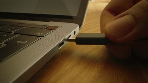 Close-up Macro Shot: Laptop on the Desk, Person Inserts USB-C Cable Adapter into Computer Port.