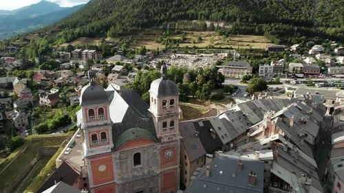 Altes Dorf mit alter Kirche am Fuße eines bewaldeten Hügels. Luftaufnahme im Tiefflug über die Gebäude von B