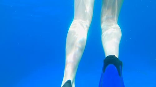 Rear Underwater View of a Young Woman Floating in the Sea with Snorkel Equipment