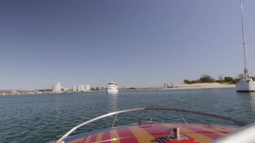 Proue d'un bateau à moteur naviguant entre d'autres plus gros bateaux près de la plage