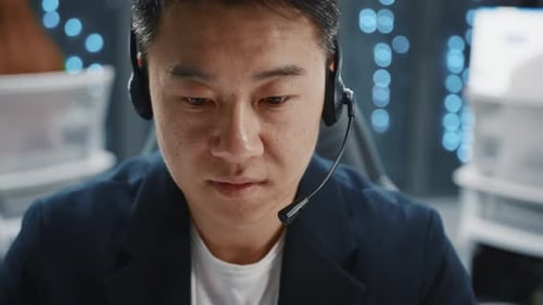 Man with Headset Typing on Laptop at Work