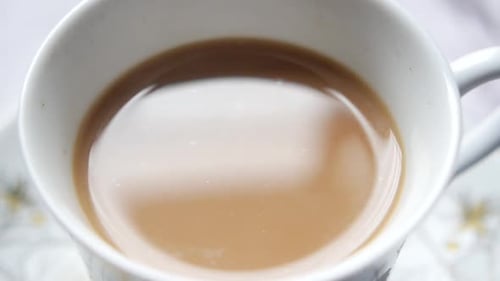 Primer plano de una taza de té con leche sobre la mesa