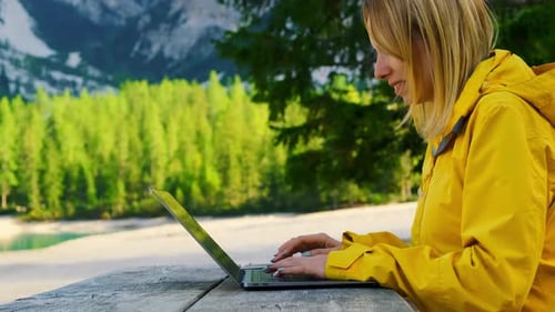 Smiling Woman Using Her Laptop with Amazing View of Mountains