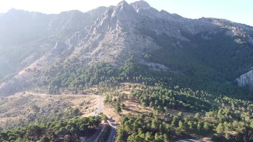 Aerial drone footage of the view of a wild road surrounded by a mountainous natural and bright lands