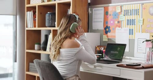 Woman with headphones sitting at desk using laptop