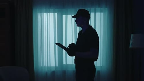 Silhouetted Man Using Tablet at Night Indoors