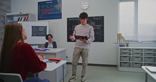 Junger Mann hält souverän Präsentationen mit einem digitalen Tablet im modernen Klassenzimmer