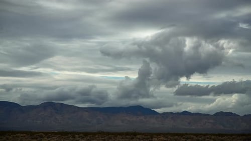 Dramatic clouds over Mojave Desert with mountain backdrop, timelapse