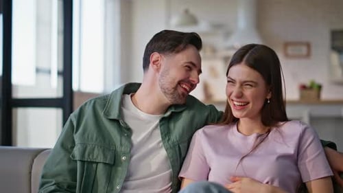Couple riant regardant un film à la télévision sur un canapé En gros plan, une paire profite d'un programme amusant