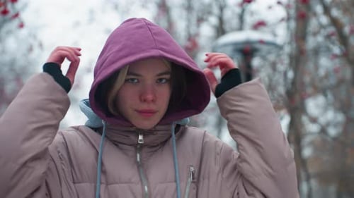 Woman Puts Up Hood in Snowy Park