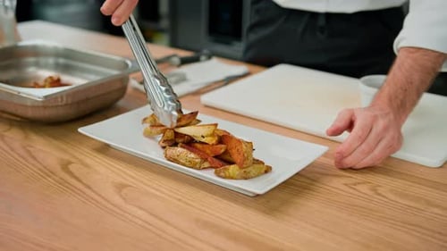 Chef Plating Delicious Crispy Potatoes in Professional Kitchen