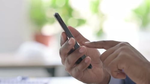 Close Up of Young African Businessman Using Smartphone