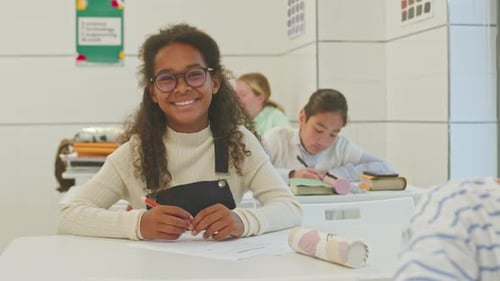 Smiling Student Working at Desk in Classroom