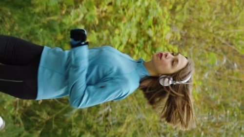 Vertical Screen Woman Jogging and Listening to Audio with Headphones
