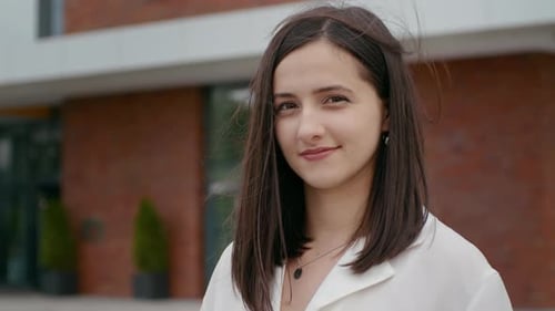 Smiling confident woman looking at camera posing alone in the street.