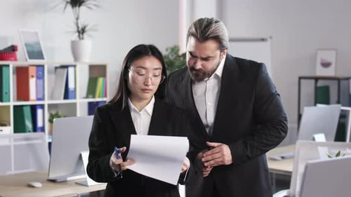 Business People Examining Reports on Clipboard at Workplace