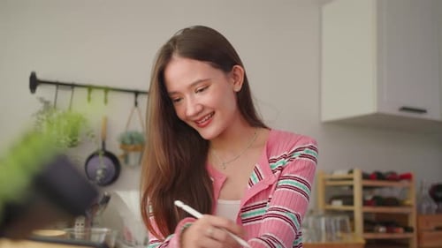 Smiling Woman Using Stylus on Tablet in Kitchen