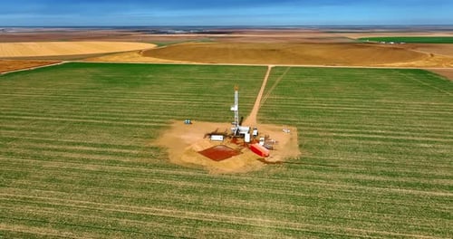 Big rectangular green field with drilling site in the middle
