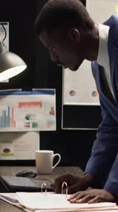 Young Adult Analyzes Charts and Graphs at Night