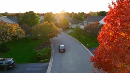 Autumn Car Drives Through Neighborhood at Sunset