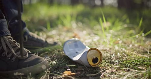 Un hombre con una bolsa de plástico recoge basura en el bosque empalándola en un palo