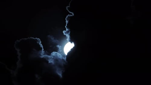 Der Mond scheint durch die Wolken am Nachthimmel und strahlt ein sanftes Mondlicht aus