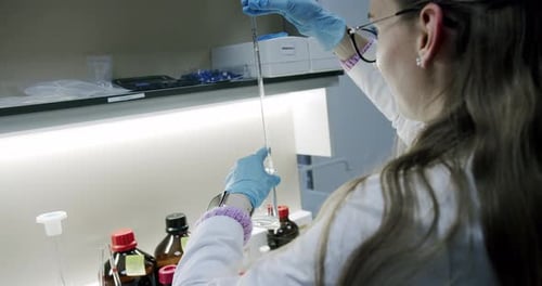 Medical research laboratory. A scientist works with a pipette and a test tube.