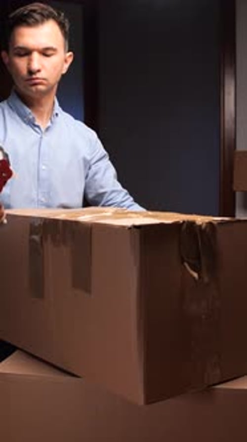 Man Taping Cardboard Box for Shipping or Moving