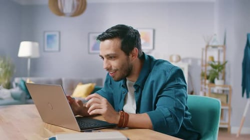 Excited young man celebrating success on laptop at home