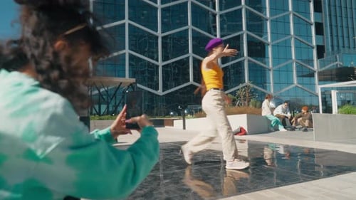 Young And Stylish Female Hip Hop Dancer Freestyling On City Street. Friend Recording A Video Of He