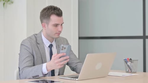 Young Adult Using Laptop and Smartphone at Workplace