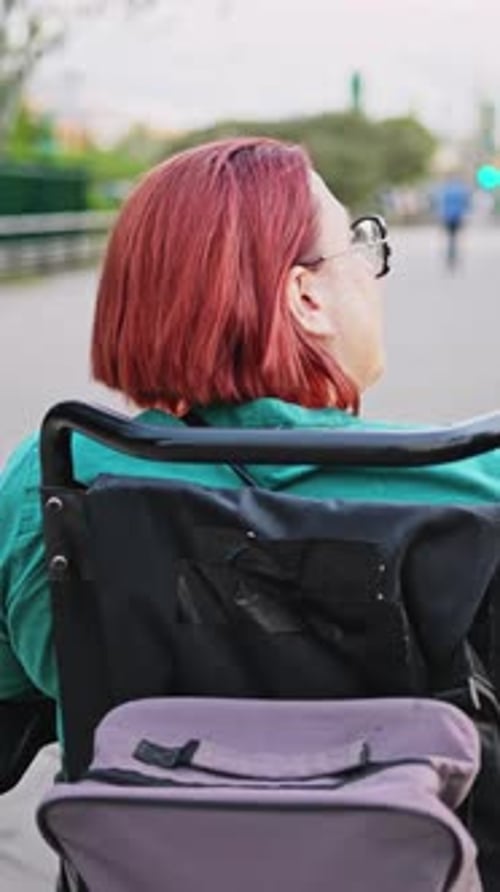 Redhead woman enjoying park ride in electric wheelchair