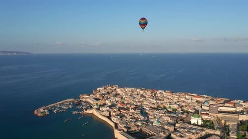 Hot air balloon passing over Acre old city port houses and Mosque at sunrise, Aerial view