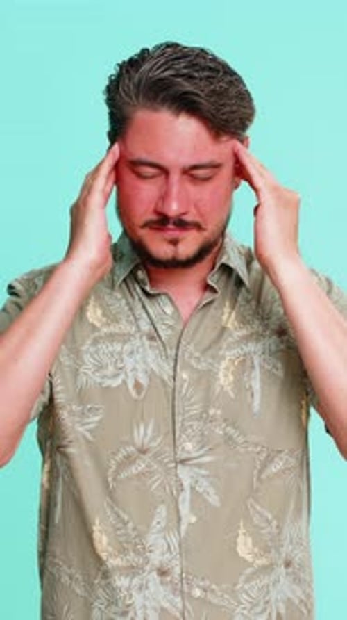 Man Rubs Temples Suffering Headache on Blue Background